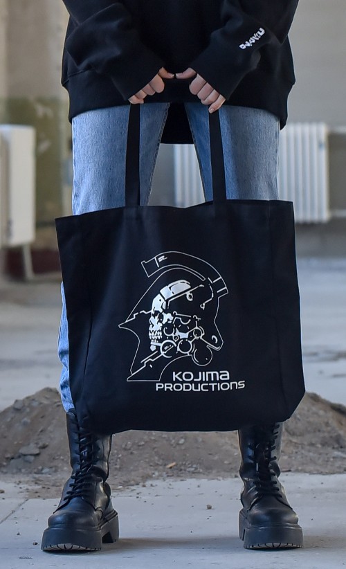 Model holding the Hideo Kojima Tote Bag from our Kojima Productions collection